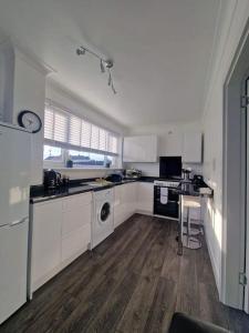 a kitchen with white cabinets and a washer and dryer at 2 Bed House Central Between Glasgow & Edinburgh in Kirk of Shotts