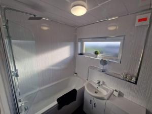 a white bathroom with a sink and a bath tub at 2 Bed House Central Between Glasgow & Edinburgh in Kirk of Shotts