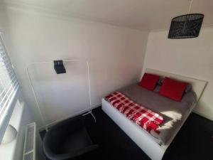 a small room with a small bed with red pillows at 2 Bed House Central Between Glasgow & Edinburgh in Kirk of Shotts
