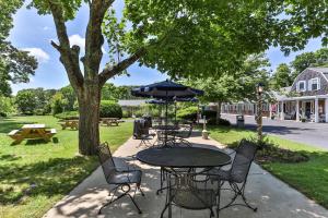 a patio with a table and chairs and an umbrella at Handkerchief Shoals Inn in Harwich