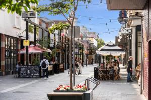 uma rua movimentada da cidade com pessoas sentadas em mesas e restaurantes em The Electric Hotel em Geelong
