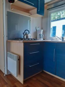 a kitchen with blue cabinets and a tea kettle on the counter at Mobilhome L'Oasis Camping le Clos Cottet in Angles