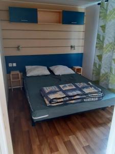 a bed in a room with blue walls and wooden floors at Mobilhome L'Oasis Camping le Clos Cottet in Angles