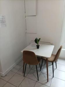 埃唐普的住宿－l'Impérial A - Gare RER à pieds，一张带两把椅子的白色桌子和一盆盆盆栽植物