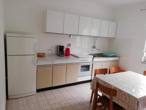 een keuken met witte kasten, een tafel en een witte koelkast bij Ferienwohnung für 8 Personen ca 90 qm in Šilo, Kvarner Bucht Krk in Šilo