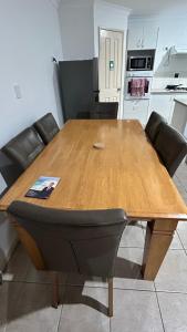 a wooden table with black chairs and a kitchen at Bickley Street in Perth
