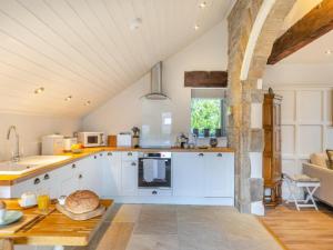 une grande cuisine avec des placards blancs et une table dans l'établissement Lyme Tree Farm Cottages, à Tideswell