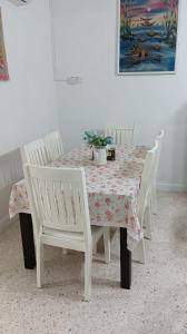 stół jadalny z białymi krzesłami i tkaniną kwiatową w obiekcie Sutera Homestay w mieście Sungai Petani