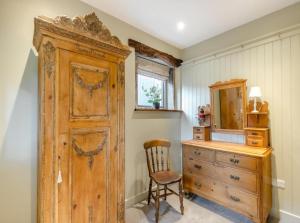 Cette chambre comprend une armoire et une commode en bois. dans l'établissement Lyme Tree Farm Cottages, à Tideswell