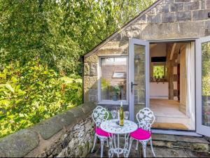 d'une terrasse avec une table et des chaises sur un mur en pierre. dans l'établissement Lyme Tree Farm Cottages, à Tideswell