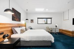 um quarto com uma cama branca, uma mesa e uma secretária em The Electric Hotel em Geelong