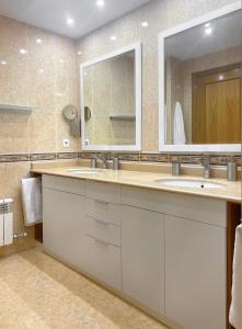 La salle de bains est pourvue de 2 lavabos et d'un miroir. dans l'établissement Piso en Logroño espacioso, con vistas y garaje, à Logroño
