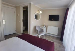 ein Schlafzimmer mit einem Bett, einem Stuhl und einem Spiegel in der Unterkunft Mr. Bird Hotel in Istanbul
