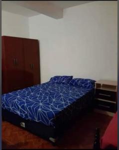ein Bett mit blauer Decke in einem Schlafzimmer in der Unterkunft Hospedaje Parano in Amaichá del Valle