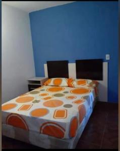 ein Bett mit einer orangefarbenen und weißen Bettdecke in einem Zimmer in der Unterkunft Hospedaje Parano in Amaichá del Valle
