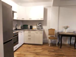 una cocina con armarios blancos y una mesa con una silla en Przy Parku, en Wyszków