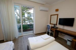 Habitación de hotel con cama, escritorio y TV. en Venüs Hotel en Antalya