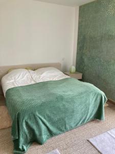 a bedroom with a bed with a green blanket on it at Maison proche de la Loire in Saint-Georges-de-Baroille