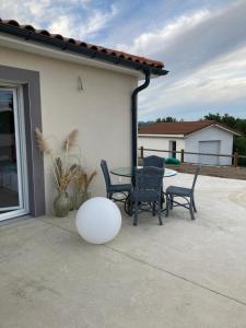 a patio with a table and chairs and a ball at Maison proche de la Loire in Saint-Georges-de-Baroille +2 photos