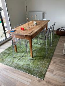 a wooden table with chairs on a green rug at Maison proche de la Loire in Saint-Georges-de-Baroille