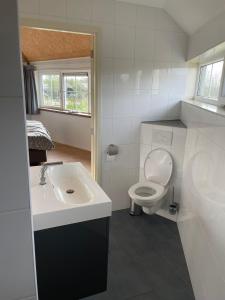 uma casa de banho branca com um lavatório e um WC em Blossom Barn Lodges em Oudewater