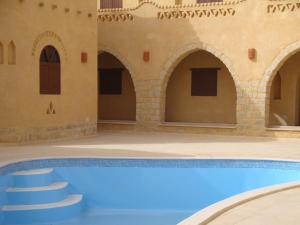 a swimming pool in a building with a house at El Beyt Farmhotel in Az Zabū