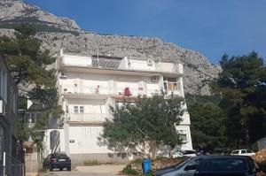 ein weißes Apartmenthaus mit einem Berg im Hintergrund in der Unterkunft Apartment Kata in Makarska