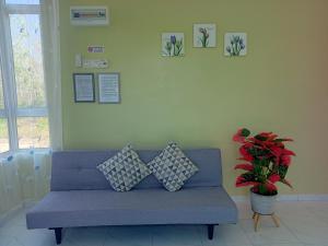 eine blaue Couch in einem Wohnzimmer mit Pflanze in der Unterkunft Minimalist Homestay D Pokok Sena in Pokok Sena