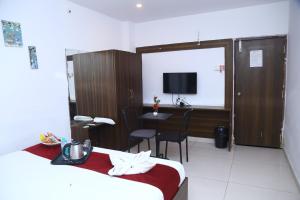 a hotel room with a bed and a desk and a television at Hotel MN Grand Shamshabad Near RGI Airport Hyderabad in Shamshabad