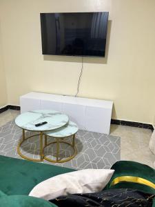 a living room with a table and a tv on a wall at Art’s Suites in Kisumu