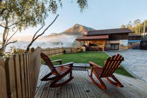 two chairs sitting on a wooden deck with a cabin at APARTAMENTOS EL CORITU, estrenamos dos apartamentos, el 4 y 5 in Nieda