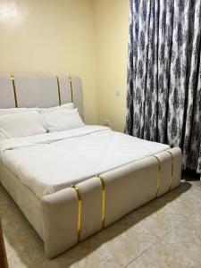 a large white bed in a bedroom next to a window at Art’s Suites in Kisumu