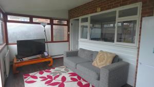 a living room with a couch and a television at Eddiwick House - Huku Kwetu Dunstable -Spacious 3 Bedroom House- Sleeps 6 - Suitable & Affordable Group Accommodation - Business Travellers in Houghton Regis