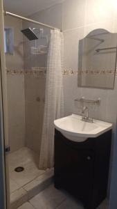 a bathroom with a sink and a shower with a shower curtain at Acogedor departamento en el centro de la ciudad in Reynosa