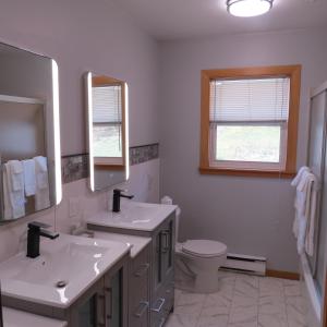 a white bathroom with two sinks and a toilet at Dockside Suites in Digby