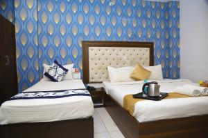 a hotel room with two beds and a blue wall at Hotel MN Grand Shamshabad Airport Zone Hyderabad in Shamshabad