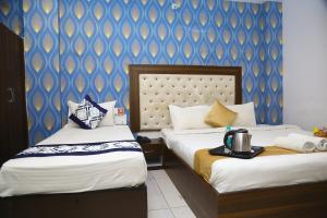 a hotel room with two beds and a blue wall at Hotel MN Grand Shamshabad Near RGI Airport Hyderabad in Shamshabad