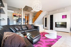 a living room with a black leather couch and a pink rug at CASA ADOSADA WELCS 137 con piscina comunitaria in Sant Feliu de Guíxols