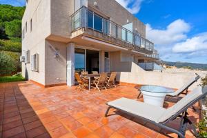 a house with a patio with a table and chairs at CASA ADOSADA WELCS 137 con piscina comunitaria in Sant Feliu de Guixols
