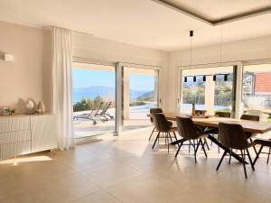 ein Esszimmer mit einem Tisch, Stühlen und Fenstern in der Unterkunft Villa Maritima-Meerblick-Infinity Pool-Luxus-Relax in Poljane