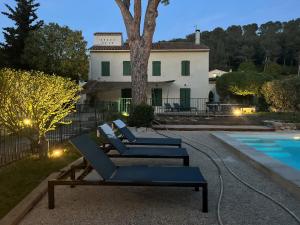 a group of lounge chairs in front of a house at Villavos- Le Bocage - Ancienne bastide Au charme authentique - piscine et jardin privés - 12 pers - Cassis in Cassis