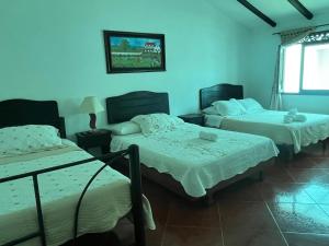 3 camas en una habitación con paredes azules en VILLA LEWANA 2, en Villa de Leyva