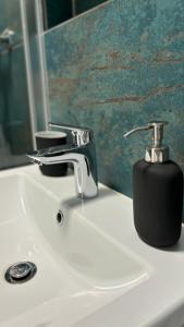 a bathroom sink with a soap dispenser on it at TRIO apartment in Piešťany