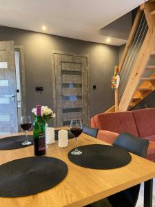 a wooden table with two glasses and a bottle of wine at Domek Pod Gwiazdami Bieszczady in Hużele