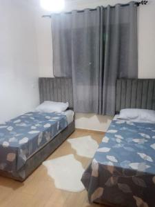 een slaapkamer met 2 bedden en een raam met gordijnen bij Cozy appartement à Mansouria res fermé 4 piscines in Mansouria
