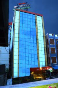 un grand bâtiment en verre avec un panneau en haut dans l'établissement Hotel MN Grand Shamshabad Airport Zone Hyderabad, à Shamshabad