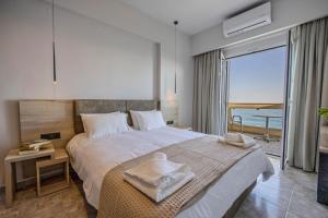 a bedroom with a bed with a view of the ocean at Santa Marina Apartments in Rodakino