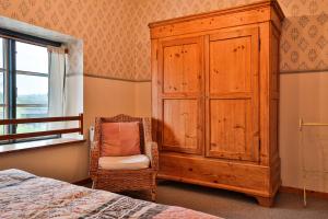 um quarto com um armário de madeira e uma cadeira em Ferienwohnung Himmelsnest em Bösdorf