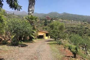 a dirt road with a yellow house on a hill at Casa Visioneros Tijarafe LaPalma in Casaquemada
