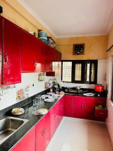 a red kitchen with a sink and red cabinets at Sanchi's Homestay 2BHK in Bhowāli
